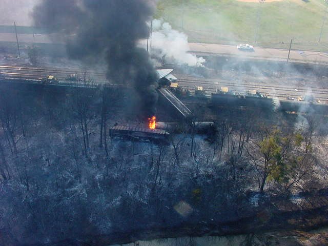 Overhead shot of the train derailment, fire started between two rail cars, charring the surrounding area.